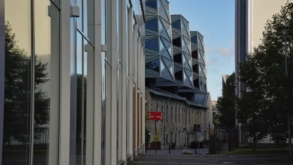 Modern glass office buildings with unique geometric facade designs in a contemporary Baltic business district.