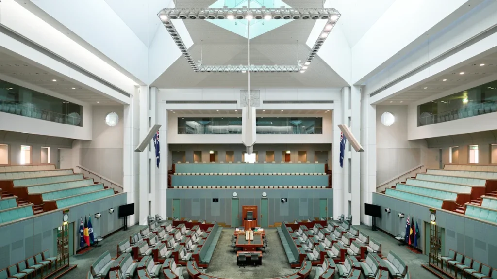 A wide-angle view of a legislative debating chamber with green benches, representing the seat of local government where Brent's new coalition will govern.