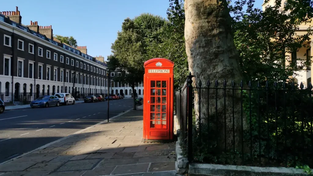 Classic red telephone box standing on a quiet London street corner.