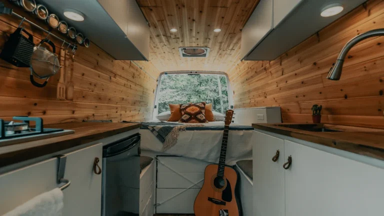 A professionally converted van interior with cedar wood paneling, white cabinetry, and a cozy living space.