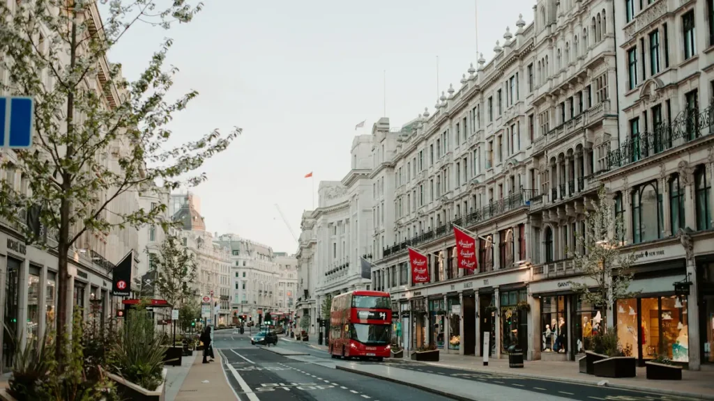 A traditional red double-decker bus driving down a historic London street.