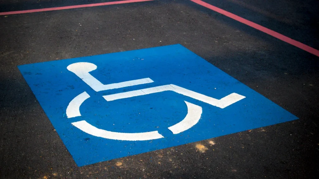 A blue and white international symbol of access painted on a parking space.
