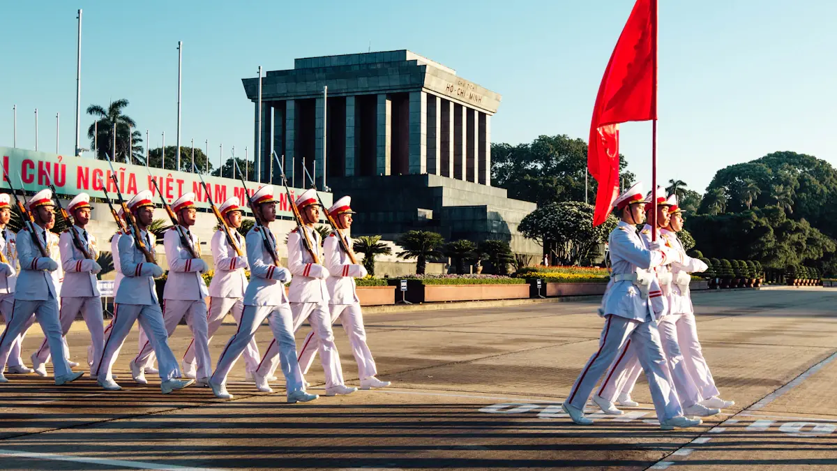 Military honor guard marching in formation outside a large, grand, columned stone building.