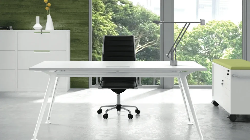 A modern, minimalist white office desk and black chair in a bright professional corporate setting.
