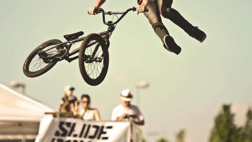 A professional BMX rider performs a high-air trick against a clear sky during an outdoor urban sports festival.