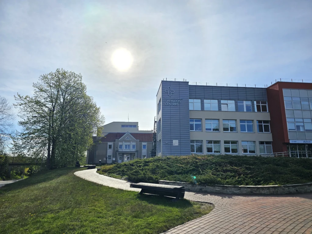 Modern health center building with a winding stone path under a bright, sunny sky.