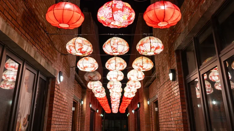 Decorative red lanterns hanging in a narrow brick alleyway at night.