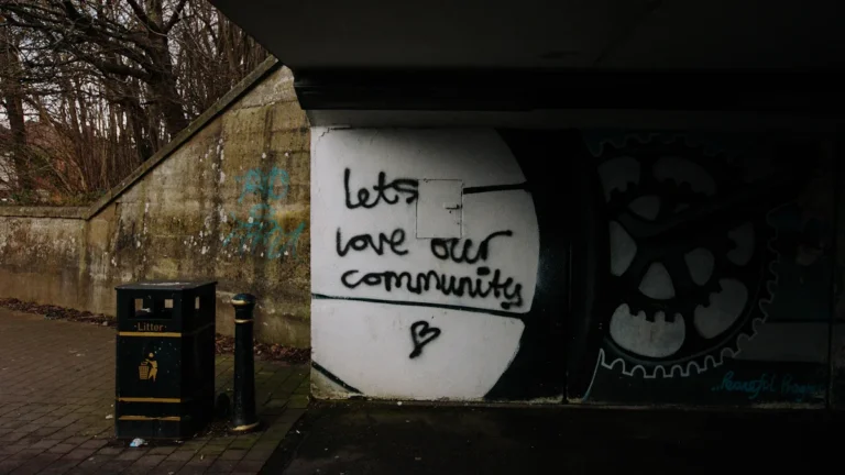 Graffiti on a wall reading 'lets love our community' with a heart symbol underneath.