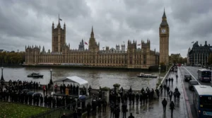 The Palace of Westminster and Big Ben overlooking a crowd gathered by the River Thames.