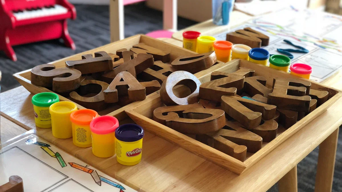 Wooden alphabet letters in trays next to colorful playdough containers on a nursery classroom table.