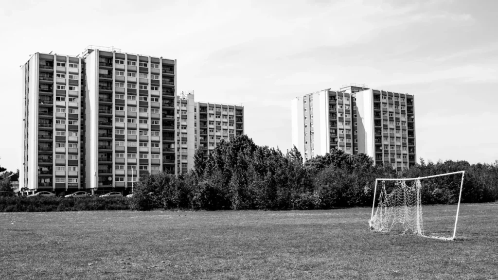 A black and white photograph of high-rise residential blocks in London across a grassy park.