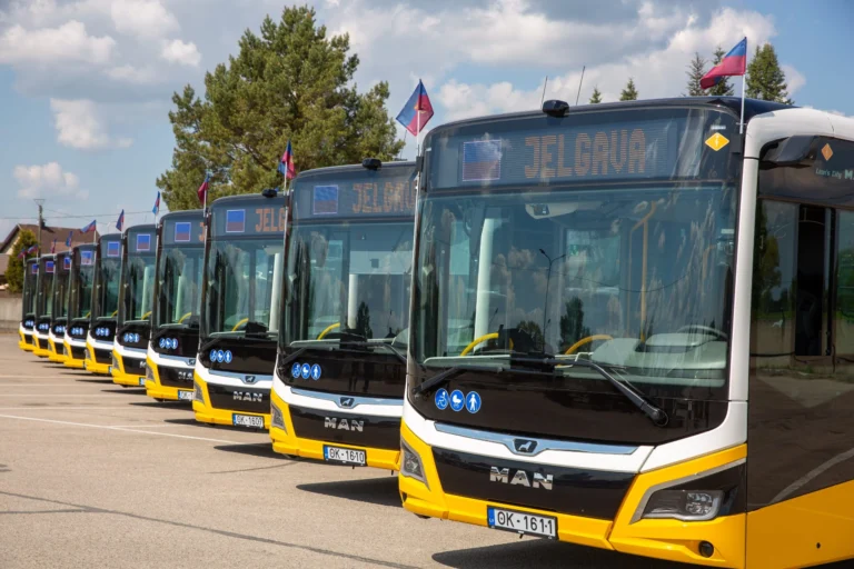 A row of yellow and black MAN buses parked outdoors with destination signs reading Jelgava.