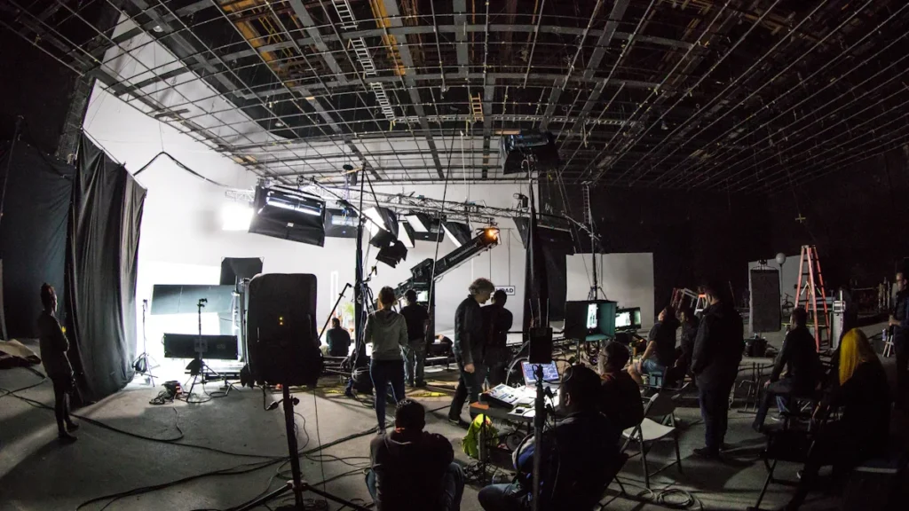 A bustling film studio set with crew members working under high ceilings and professional lighting equipment, representing internship opportunities in the film industry.