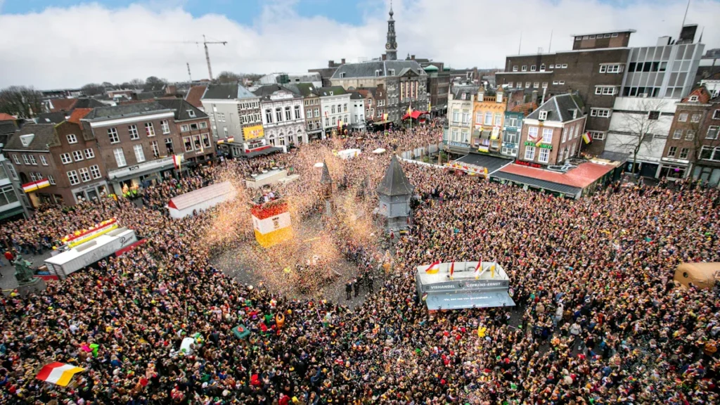 Aerial view of a crowded historic plaza filled with people celebrating a festive city parade.