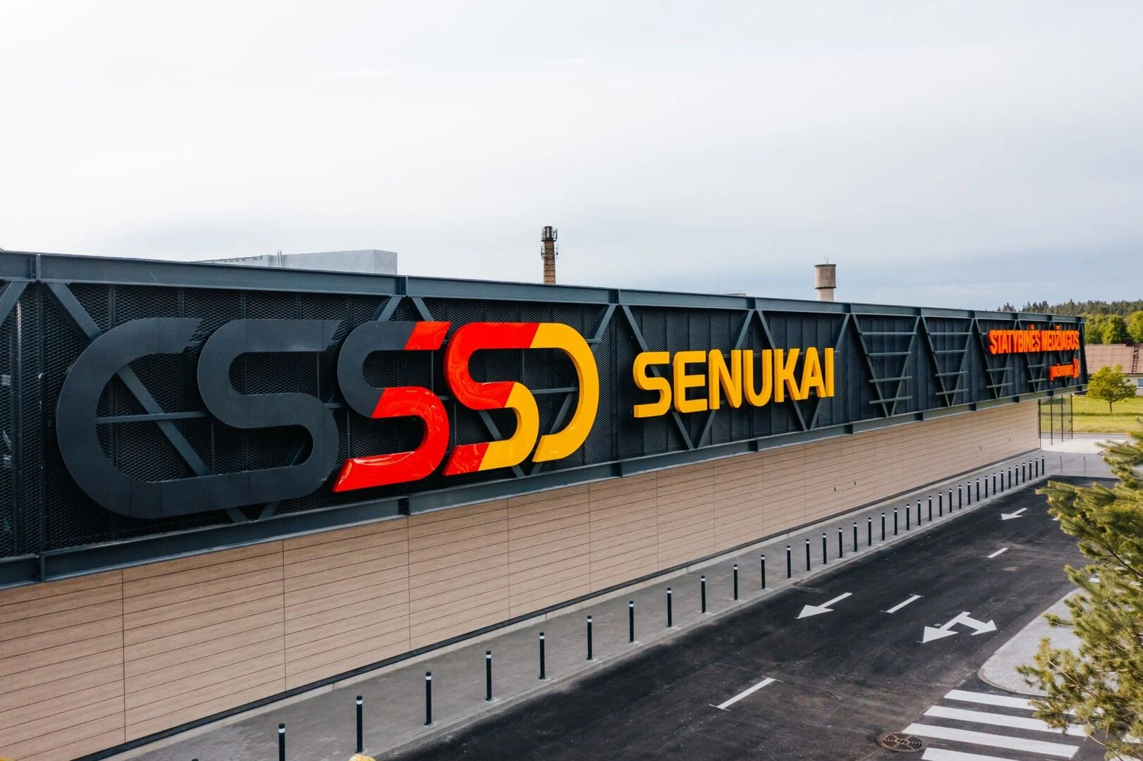 Exterior view of a modern building featuring prominent yellow and red Senukai brand signage.
