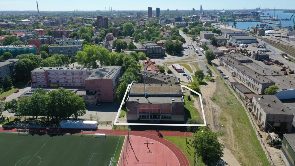 Aerial shot of a city building outlined in white near a sports field and harbor.