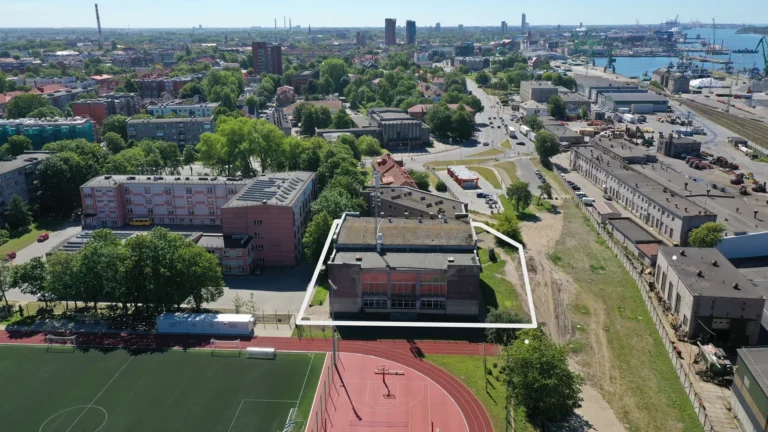 Aerial shot of a city building outlined in white near a sports field and harbor.