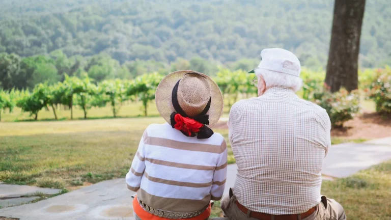 An elderly couple sitting together outdoors, representing the benefits of quality social care.