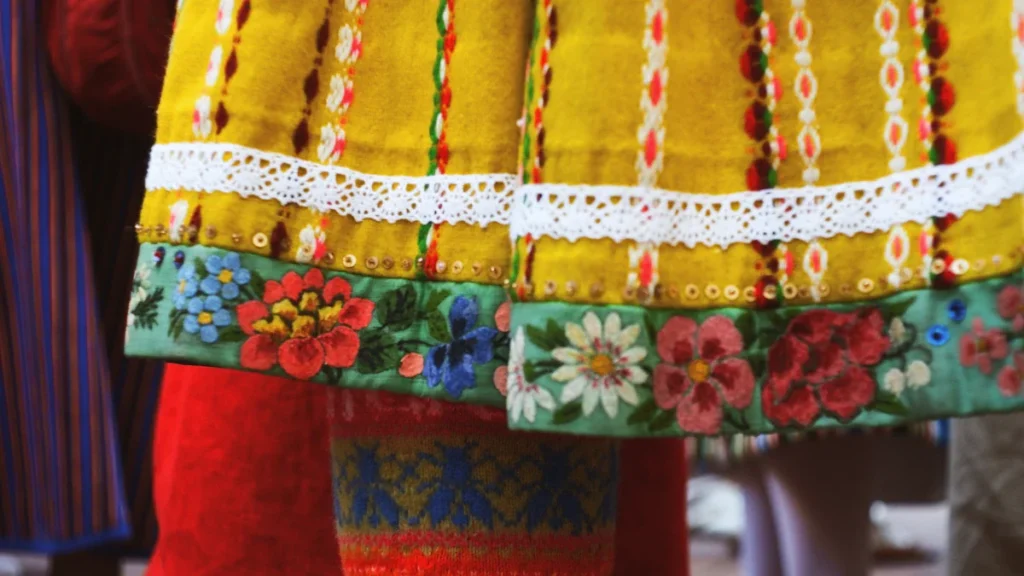 Close-up of a yellow folk dress with colorful floral embroidery and delicate white lace.