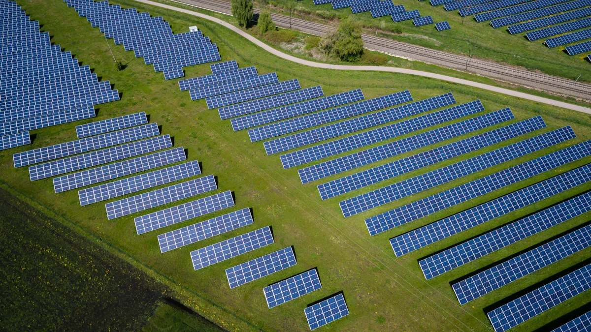 An aerial view of a large-scale solar farm with rows of blue panels on green grass.