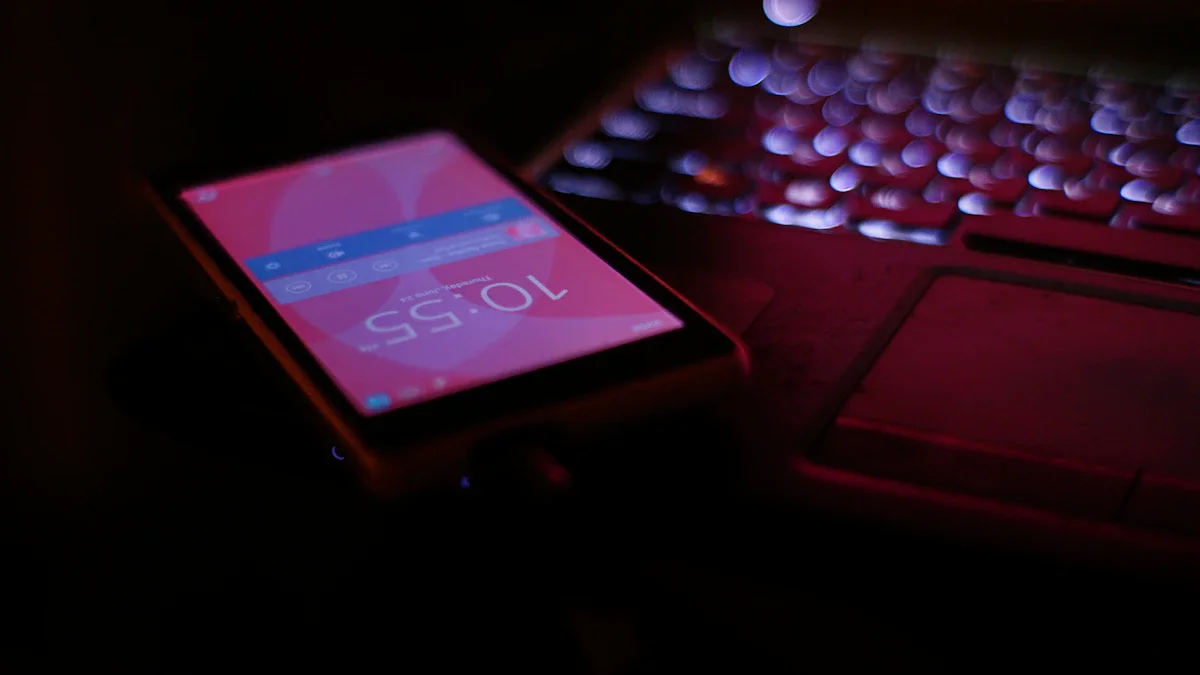 A glowing smartphone screen rests on a laptop keyboard in a dark room at night.