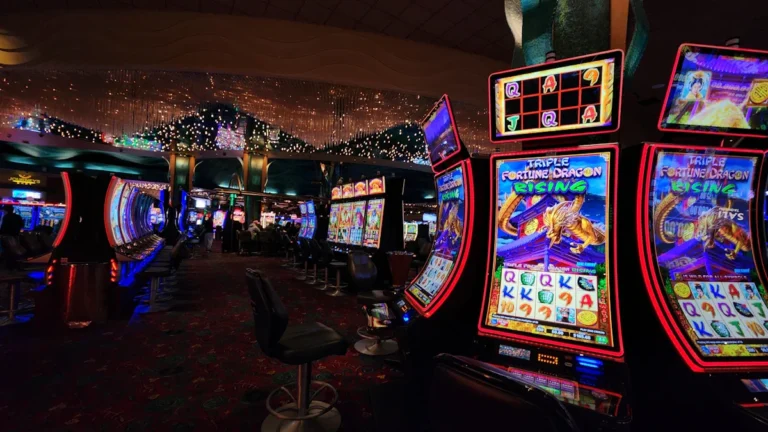 A wide view of a modern casino floor filled with rows of illuminated slot machines.
