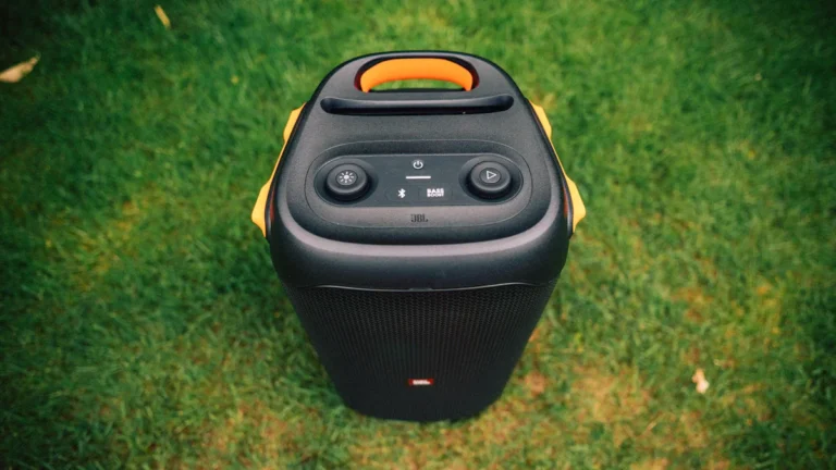 A large portable black party speaker sitting on a green lawn.