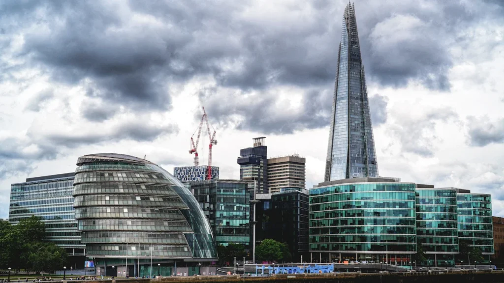 View of the London skyline featuring City Hall and the Shard under a dramatic sky.