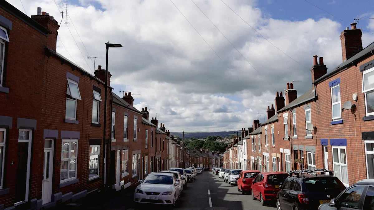 A long residential street in a UK city featuring red brick terraced houses and parked cars.