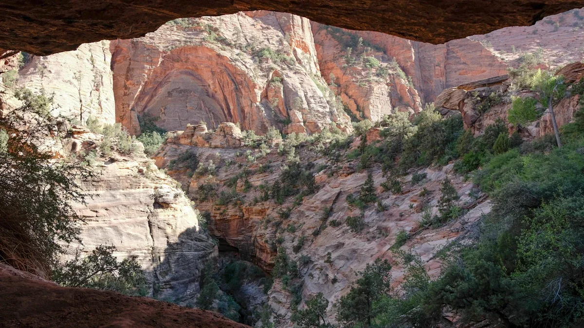 A view from the dark interior of a cave looking out onto a rocky canyon landscape.