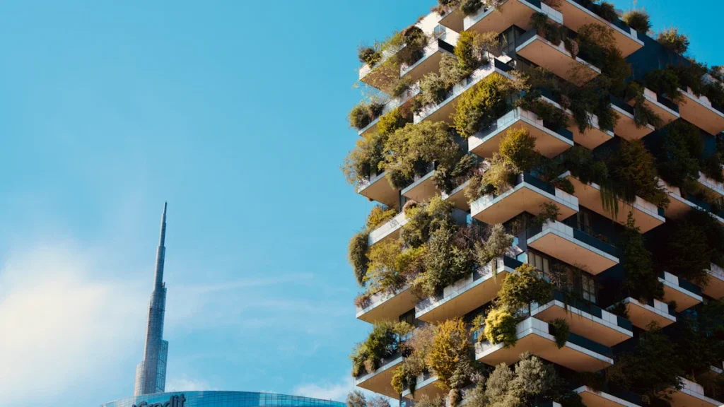A modern residential building featuring balconies covered in lush green plants and vertical gardens.