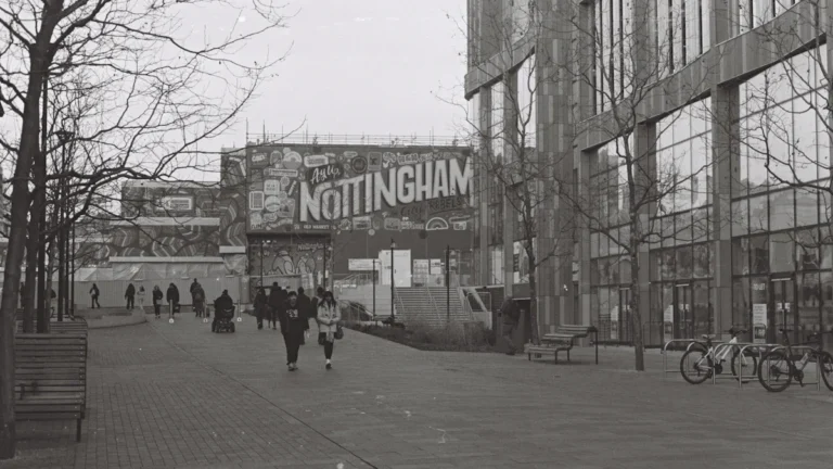 People walking through a Nottingham city street featuring local signage in black and white.