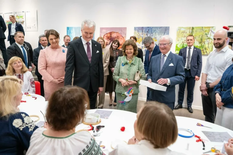 Lithuanian President, Swedish King, and their wives observe women crafting at a white round table.