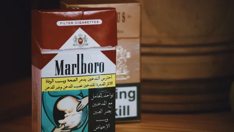 A packet of Marlboro cigarettes with Arabic health warnings on a wooden background.