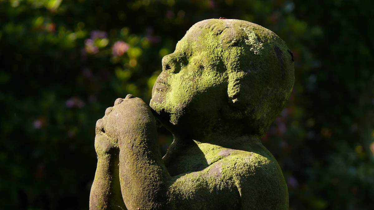 Close-up of a moss-covered stone cherub statue praying, symbolizing remembrance and childhood innocence.