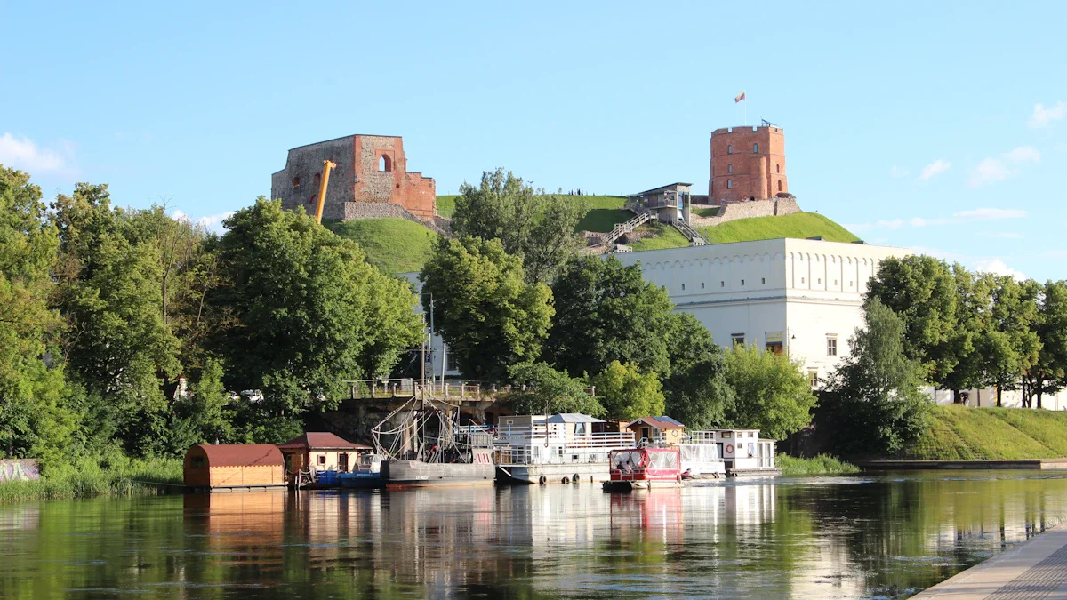 A wide-angle view of the Vilnius skyline featuring the Neris River and historic architecture at dusk.