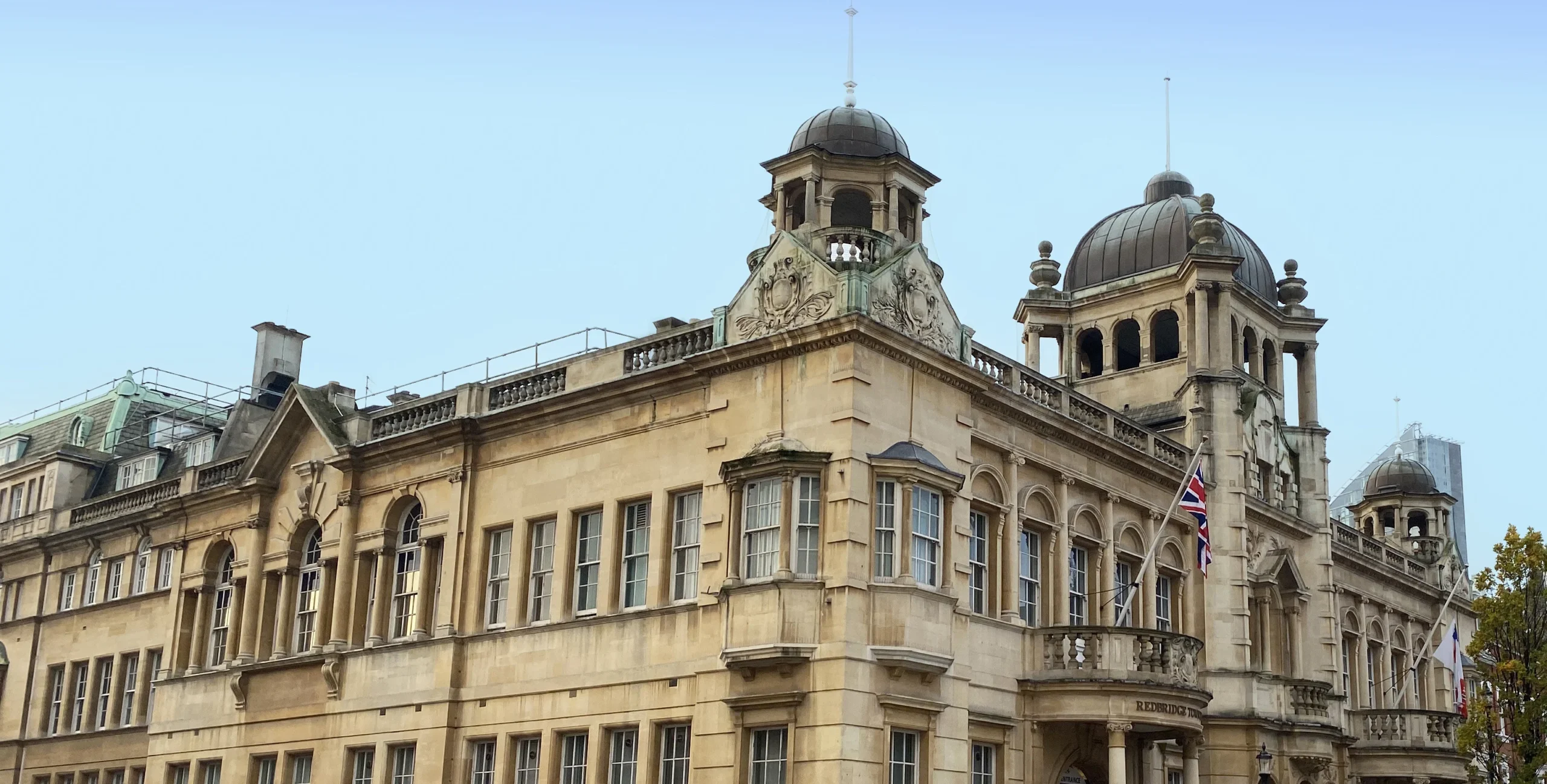 Historic stone town hall with domed towers and a Union Jack flag flying from the balcony.