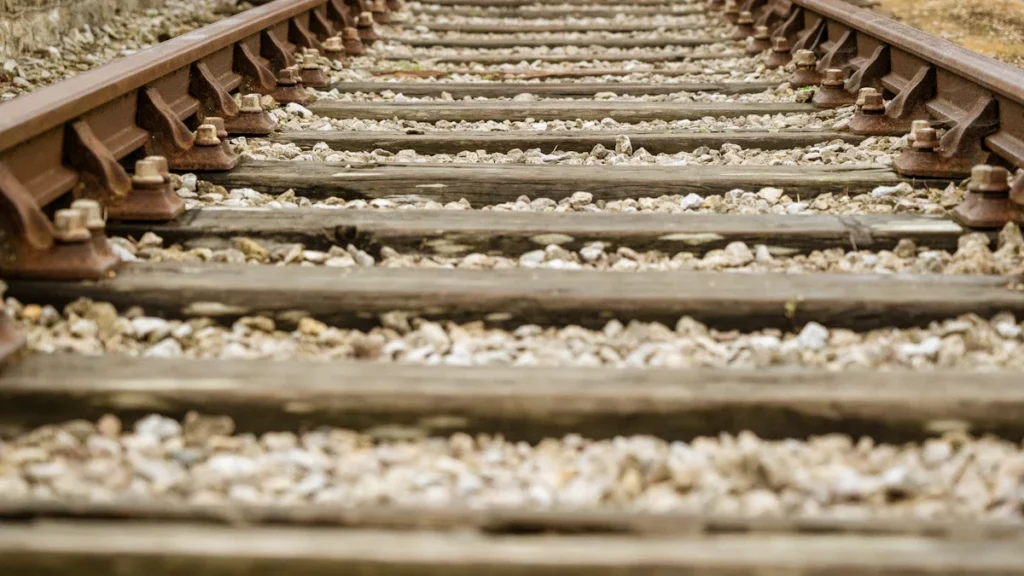 A low-level view of railway tracks and wooden sleepers on grey stones in Bournemouth, UK.