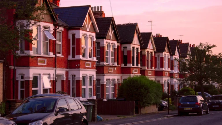A row of Victorian terraced houses along a street in London during the evening.