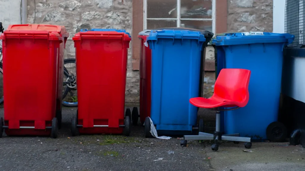 Colorful household wheelie bins lined up outside a residential building in the UK.
