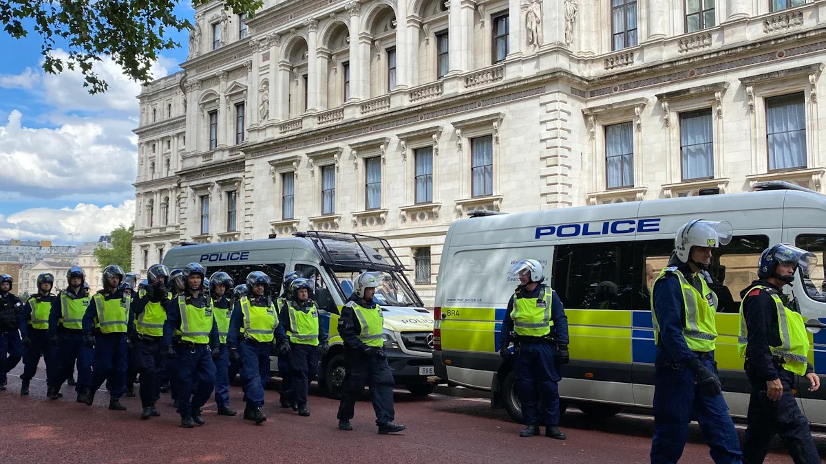 A large squad of police officers in high-visibility vests and riot helmets march through Westminster, London.