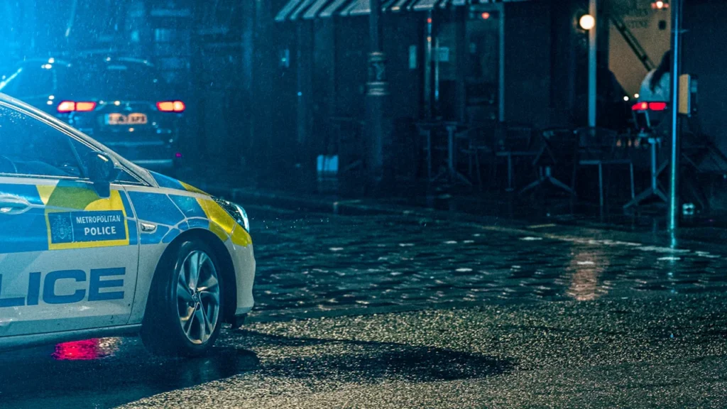 Metropolitan Police car parked on a wet London street during a night patrol.