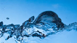 Close-up of turbulent water splashing against a clear, solid blue background.