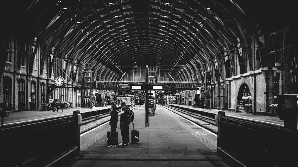 Black and white view of a busy train station platform with commuters.