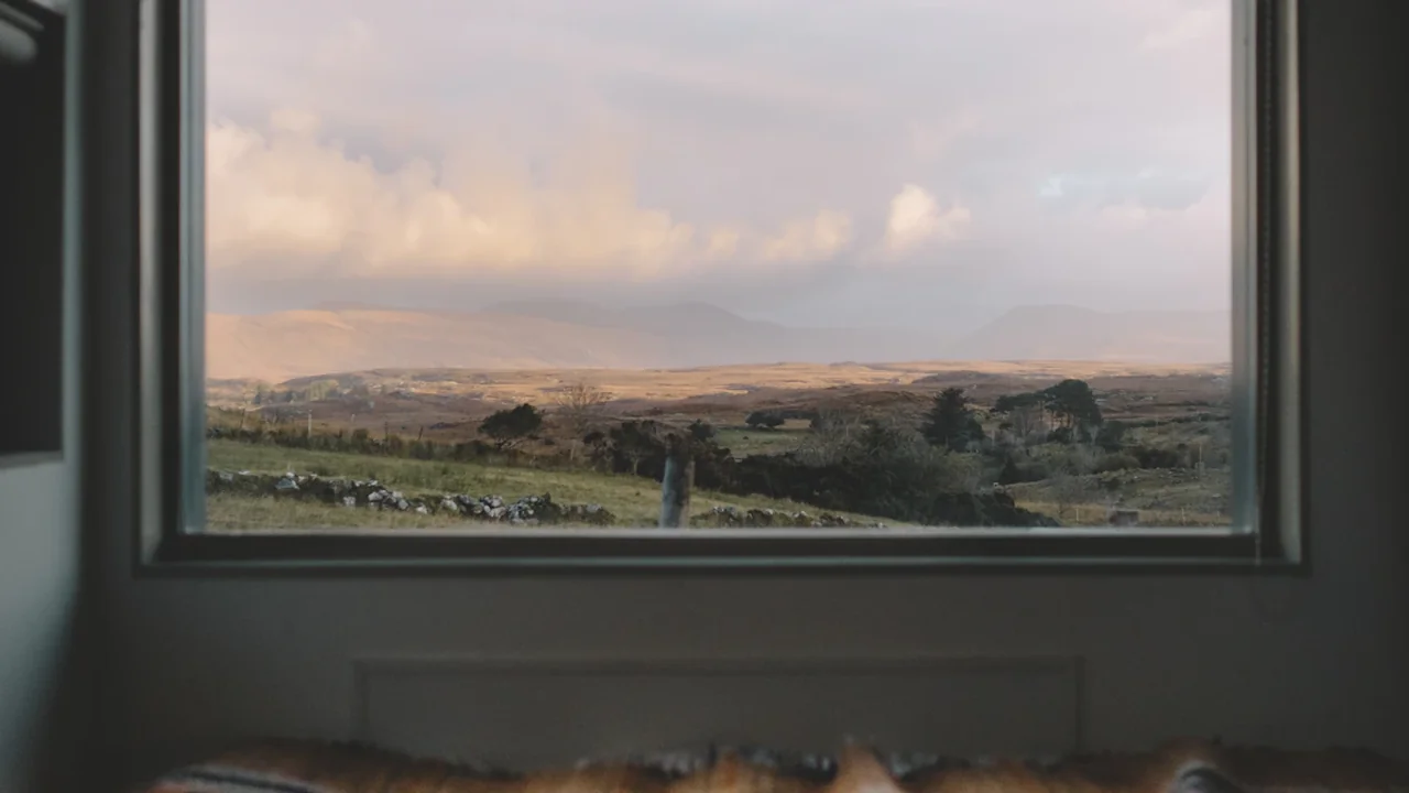 A bedroom view looking out of a large window onto rural British landscape.