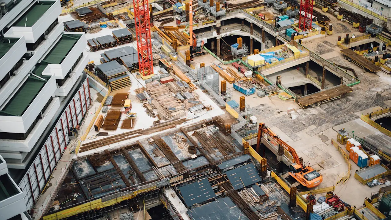 Aerial view of a large urban construction site with rising high-rise concrete structures.