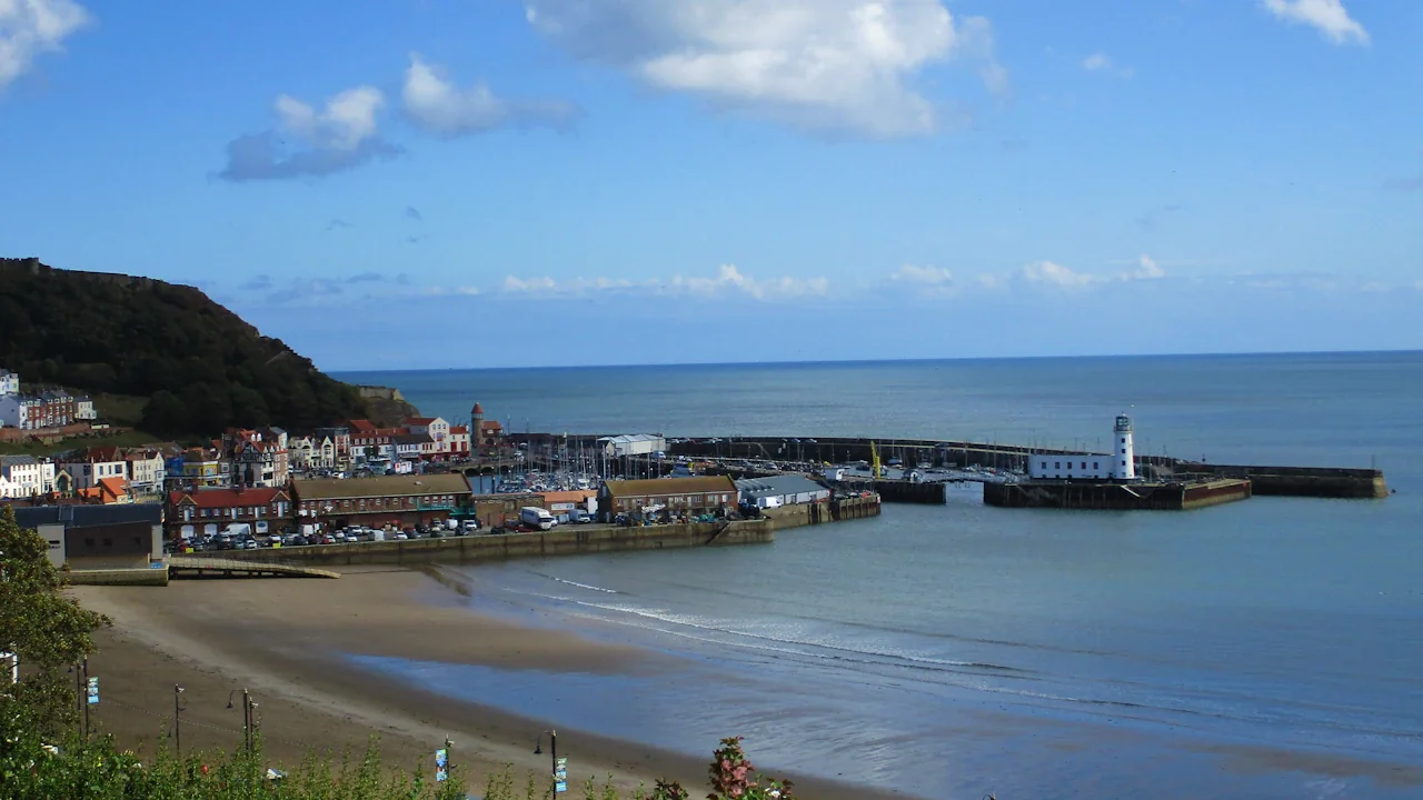 Panoramic view of Scarborough harbour featuring the lighthouse and West Pier coastal buildings.