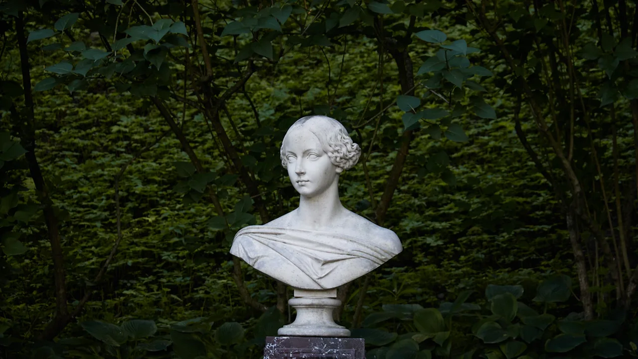 A classical marble bust of a historical figure situated in Crystal Palace Park greenery.