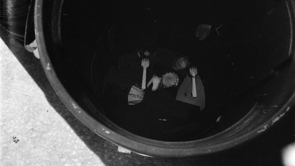 A black and white overhead view of discarded food scraps inside a waste bin.
